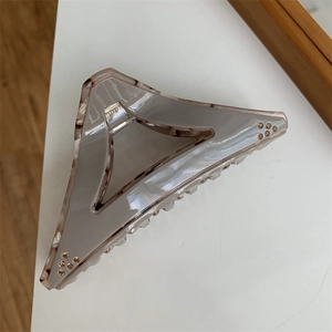 Detail of a large geometric triangle hair claw with grey resin, tortoiseshell trim and rhinestones