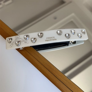 Detail of white acetate hair clip with heart rhinestones and gold France Handmade text