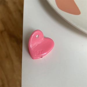 Close-up of a pink heart-shaped mini hair claw with sparkling rhinestone and engraved detail