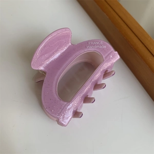Detail der eleganten violetten Haarklammer aus Acetat mit feinem Glitzer und Logo-Prägung