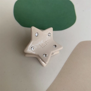 Macro view of cream star hair claw clip with crystal rhinestones and engraved logo