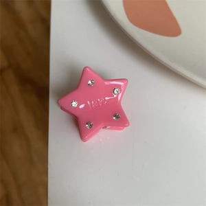 Close-up of pink star-shaped hair clip featuring clear rhinestones and engraved lettering