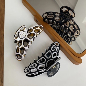 Detailed macro of French style acetate hair claws with geometric hollow design and logo