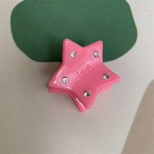 Detail of pink star mini hair claw clip featuring sparkling rhinestones and lar. engraving