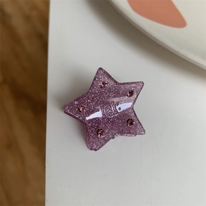 Close-up of a purple glitter star hair claw clip with pink rhinestones and hair engraving