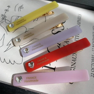 Set of five colorful rectangular hair clips with heart rhinestones and gold text