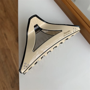 Macro view of geometric beige triangle hair claw clip with rhinestones and black borders