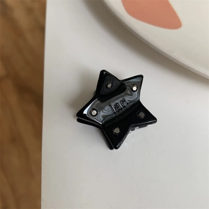 Macro shot of a black star-shaped hair clip with silver dots and engraved text