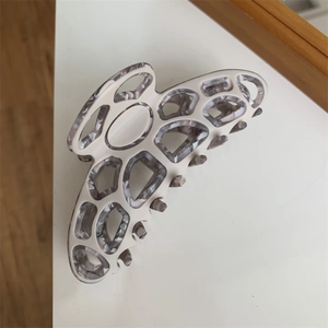 Detail of butterfly hair claw with beige and grey marble texture and geometric cutouts