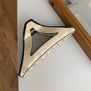 Close-up of geometric triangle hair claw clip with beige resin and rhinestone accents