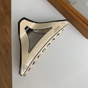 Detail of large beige triangle hair claw clip with rhinestones and black borders