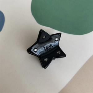 Macro shot of a mini black star hair clip with crystals and the engraved lar. logo