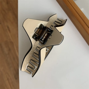 Macro view of large cream geometric shark hair clip with black border and sturdy spring