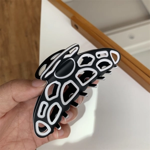 Detailed close-up of a large black and white butterfly-shaped claw clip for hair