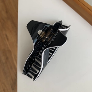 Detail of a large black and white geometric hair claw clip with a strong metal spring