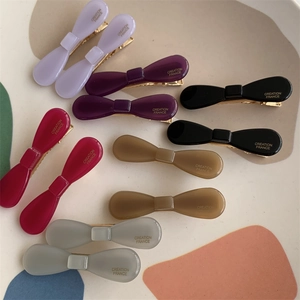Detail of colorful acetate bow hair clips with gold-toned Creation France lettering