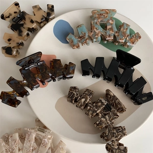 Macro detail of French style acetate hair claw with wavy teeth and metal spring mechanism