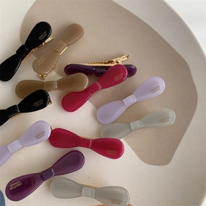 Detailed close-up of colorful acetate bow hair clips with gold metal duckbill clips