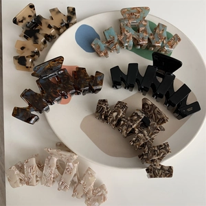 Detailed close-up of large acetate hair claws in various marble patterns on a tray