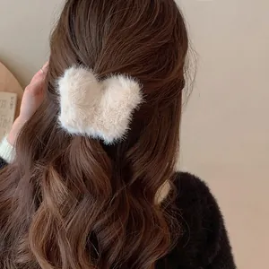 Detailansicht einer weichen beigen Plüsch-Schmetterlingshaarklammer in braunem Haar