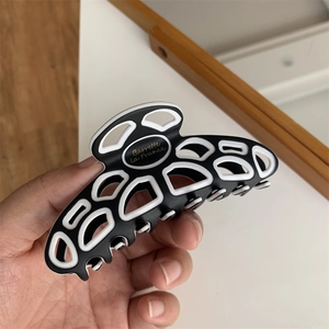 Detailed close-up of large black and white geometric pattern hair claw with gold lettering