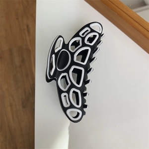 Macro view of a black and white geometric pattern hair claw clip on a surface