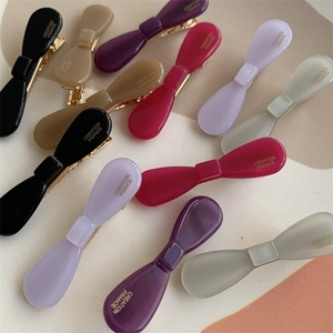 Flat lay of small bow-shaped acetate hair clips in Morandi colors with gold lettering