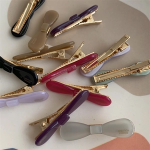 Detailed macro view of Morandi-colored acetate bow hair clips with gold base duckbill design