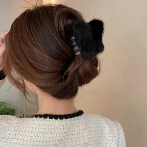 Detail der flauschigen schwarzen Haarspange im Schmetterlingsdesign am Haarknoten