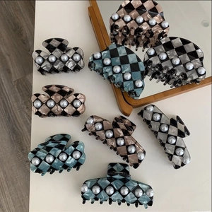 Detail of checkered acetate claw clips with pearl accents in black, blue, and brown