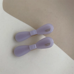 Detailed side view of purple acetate bow hair clips with gold Creation France lettering