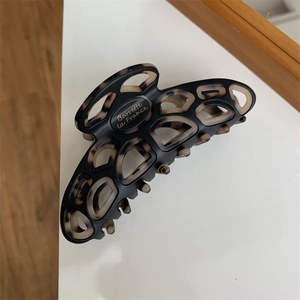 Detail of a large matte black and tortoiseshell hair claw with gold French lettering