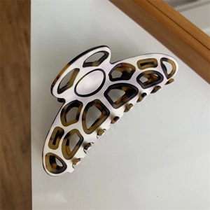 Detail view of large geometric hair claw clip featuring cream and leopard print accents
