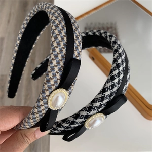 Close-up of houndstooth headband with black bow and large pearl detail on hand