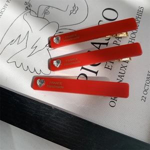 Detailed macro view of vibrant red acetate hair clips with heart-shaped crystal and gold text