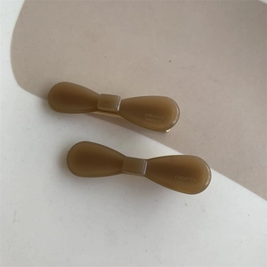 Detail of amber brown bow hair clips with matte finish and golden metal base clips