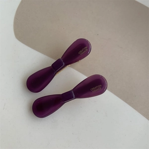 Detailed view of dark purple acetate bow hair clips with elegant gold script lettering