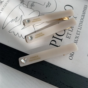Detailed view of three cream resin rectangular hair clips with heart-shaped rhinestones