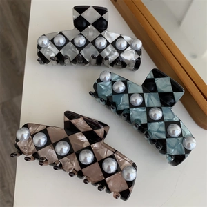 Detailed view of three checkered hair claws with elegant pearl inlays in various colors