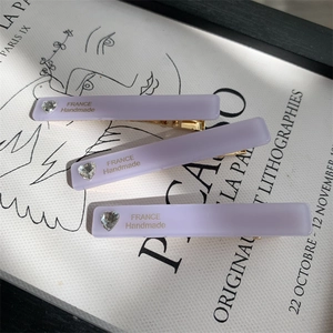 Detail of lavender matte hair clips with heart rhinestone and gold France lettering