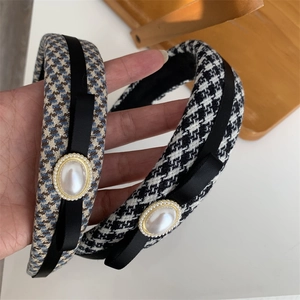 Detail of houndstooth headband with black bow and vintage pearl accent on soft sponge base