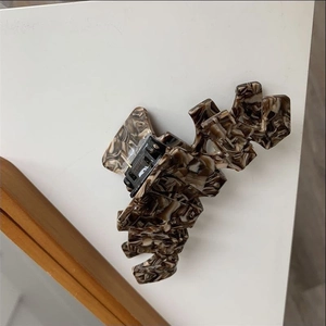 Macro detail of tortoiseshell acetate hair claw clip showing marble texture and metal spring