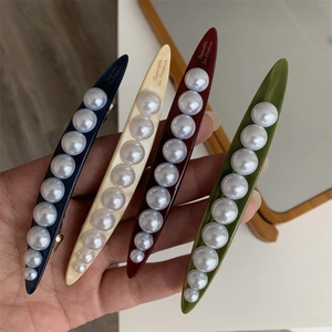 Detailed macro view of long leaf hair clips with graduated pearls in four different colors