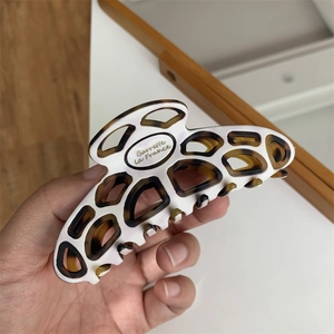Detail of large acetate hair claw clip with tortoiseshell pattern and gold lettering