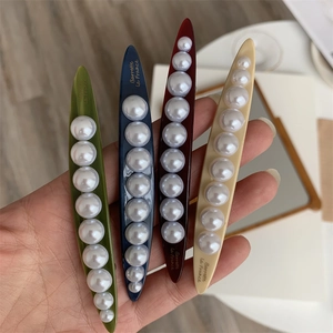 Detailed macro of four resin pearl hair clips in green, navy, burgundy and cream