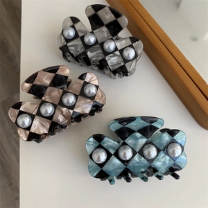 Detail of checkered hair claws with pearls in black-grey, brown, and blue acetate