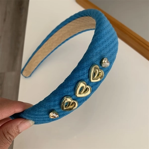 Detail of blue padded headband featuring gold heart charms and sparkling rhinestones