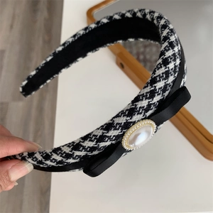 Detail of thickened houndstooth headband with black satin bow and large pearl embellishment