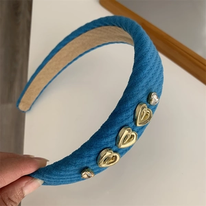 Detail of blue striped velvet headband with gold heart charms and sparkling crystals