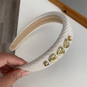 Detail of cream sponge headband with gold heart metal charms and amber rhinestones